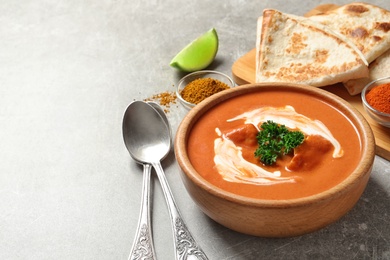 Photo of Delicious butter chicken served on grey table, space for text. Traditional indian Murgh Makhani
