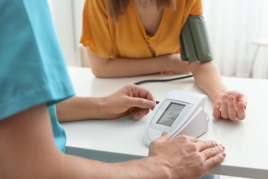 Photo of Doctor checking patient's blood pressure in hospital, closeup. Cardiology concept