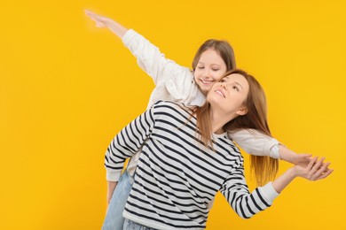 Happy mother with her cute daughter on orange background. Space for text