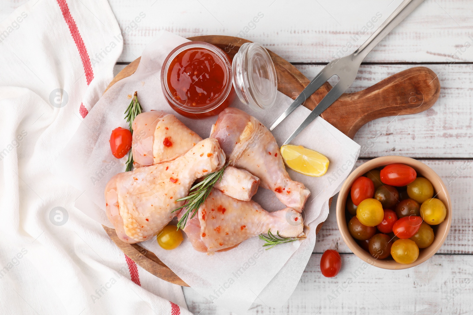 Photo of Marinade, raw chicken drumsticks, tomatoes and rosemary on white wooden table, flat lay