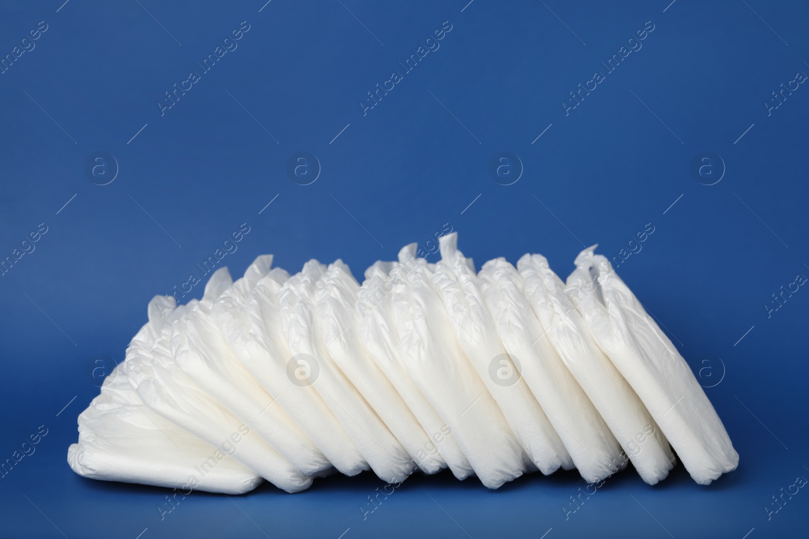 Photo of Pile of baby diapers on blue background