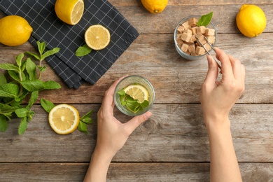 Photo of Young woman making delicious mint julep cocktail at table