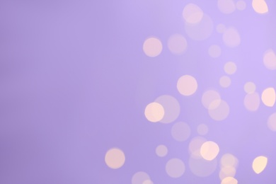 Photo of Blurred view of festive lights on violet background, space for text. Bokeh effect