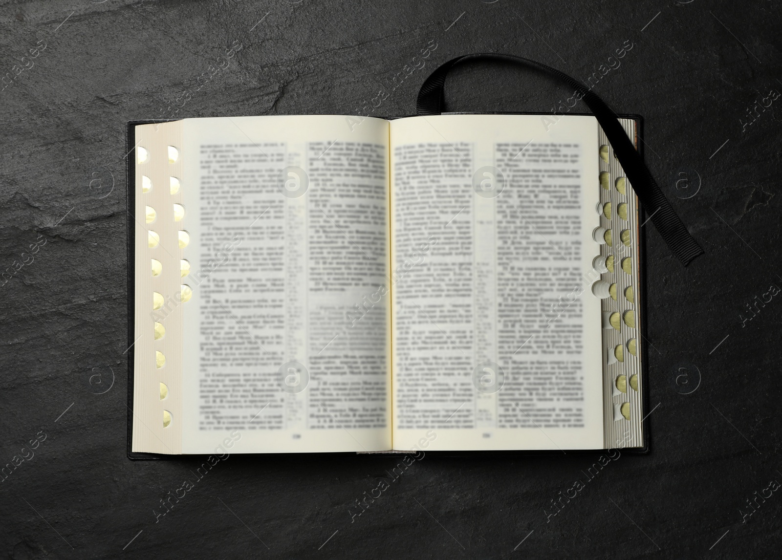 Photo of Open Bible on black table, top view. Christian religious book