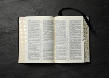 Photo of Open Bible on black table, top view. Christian religious book