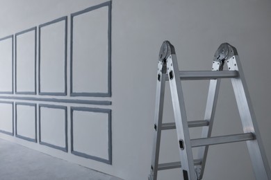 Photo of Metal ladder near fresh painted walls indoors