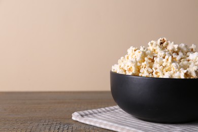 Photo of Delicious popcorn in bowl on wooden table. Space for text