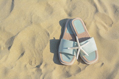 Photo of Stylish slippers and dry starfish on sandy beach, flat lay. Space for text