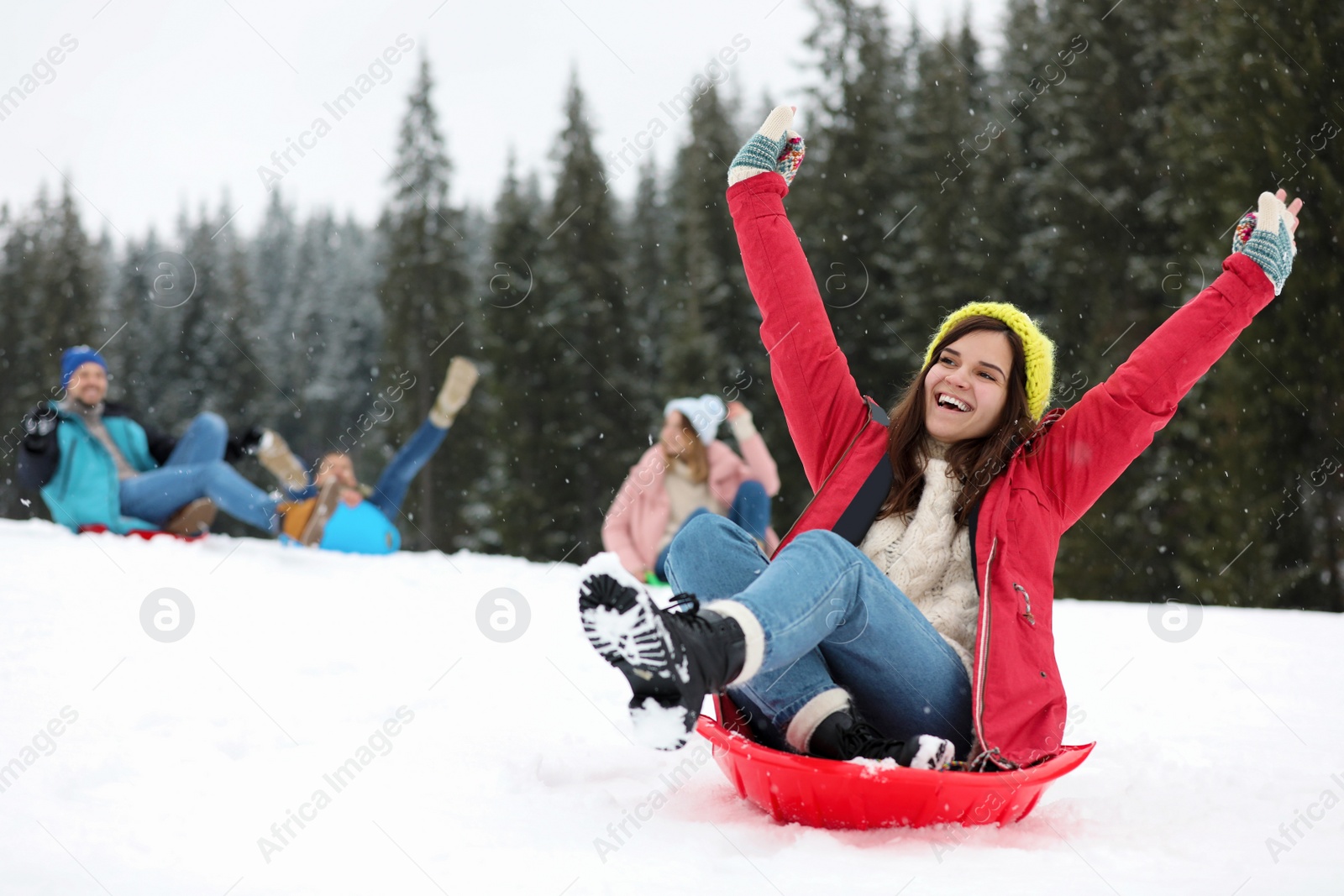 Photo of Happy friends sliding on sleds outdoors. Winter vacation