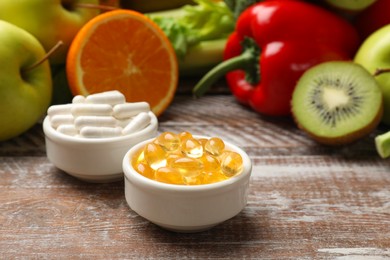 Photo of Dietary supplements. Different pills in bowls and food products on wooden table