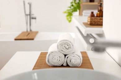 Photo of Rolled soft towels on white table in bathroom