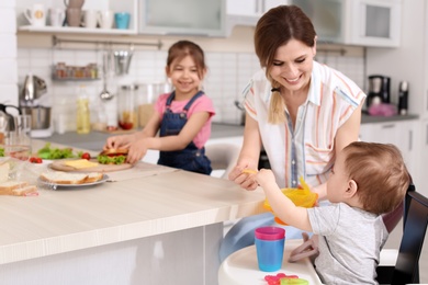 Housewife preparing dinner with her children on kitchen