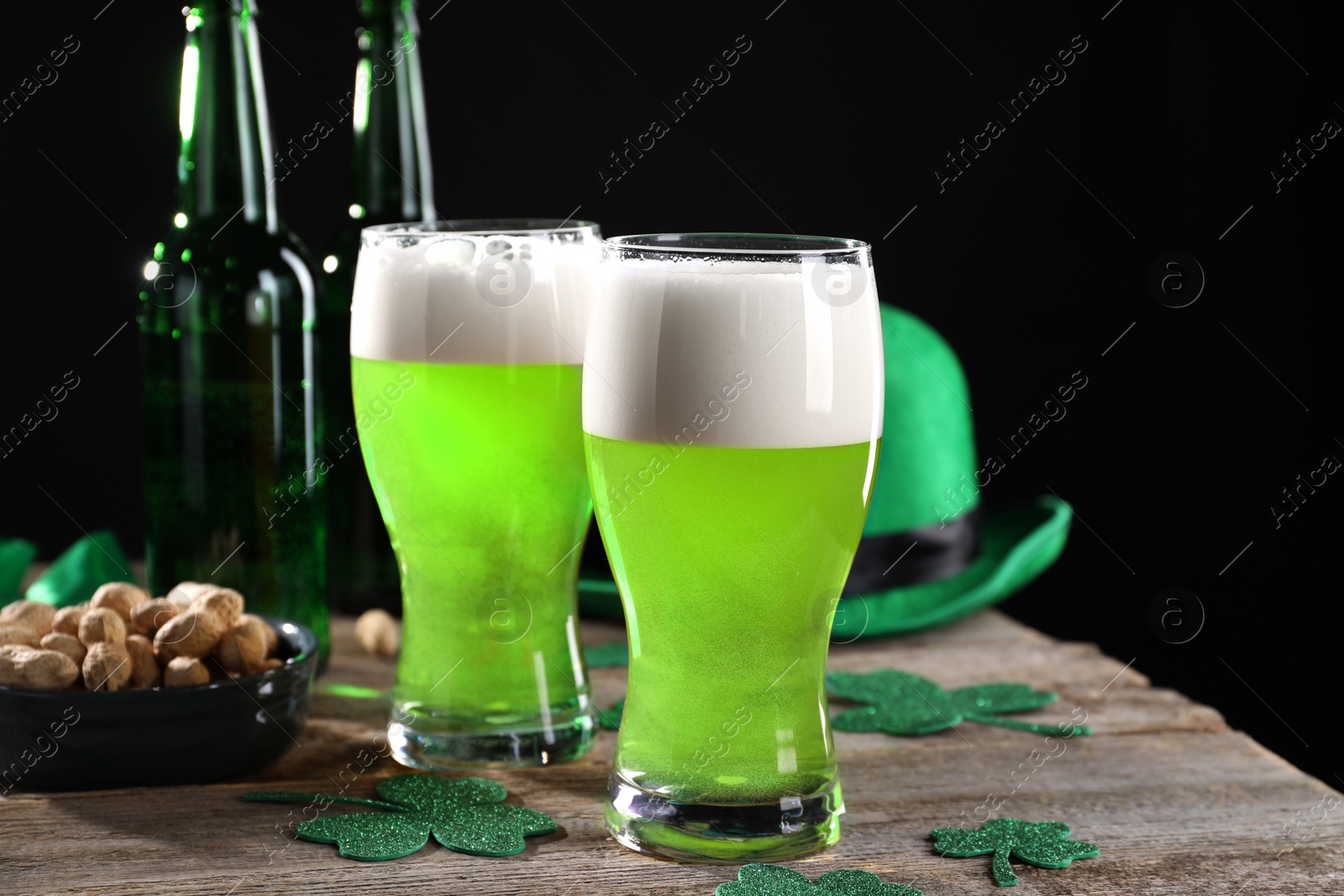 Photo of St. Patrick's day party. Green beer, nuts, leprechaun hat and decorative clover leaves on wooden table