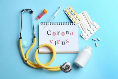 Flat lay composition of medications and notebook with words CORONA VIRUS on light blue background