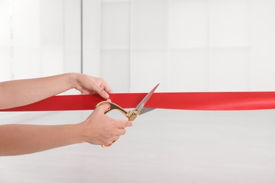 Woman cutting red ribbon on blurred background. Festive ceremony