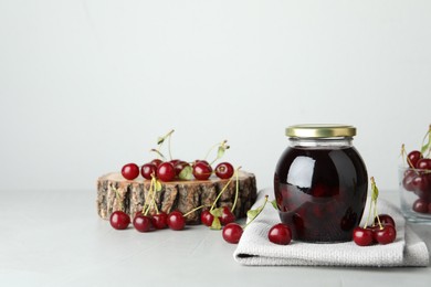 Photo of Jar of pickled cherries and fresh fruits on light table. Space for text