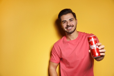 Photo of MYKOLAIV, UKRAINE - NOVEMBER 28, 2018: Young man with Coca-Cola can on color background, space for text