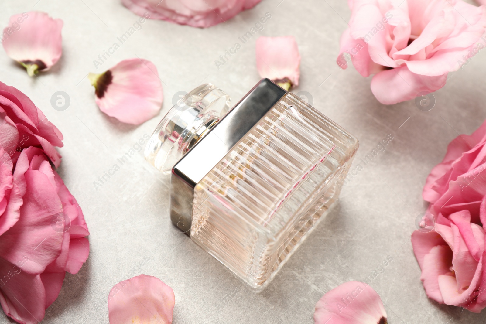 Photo of Composition with bottle of perfume and eustoma flowers on grey textured background