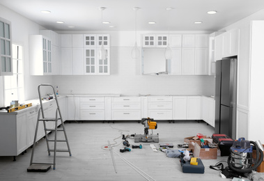 Renovated kitchen interior with stylish furniture, refrigerator and maintenance equipment