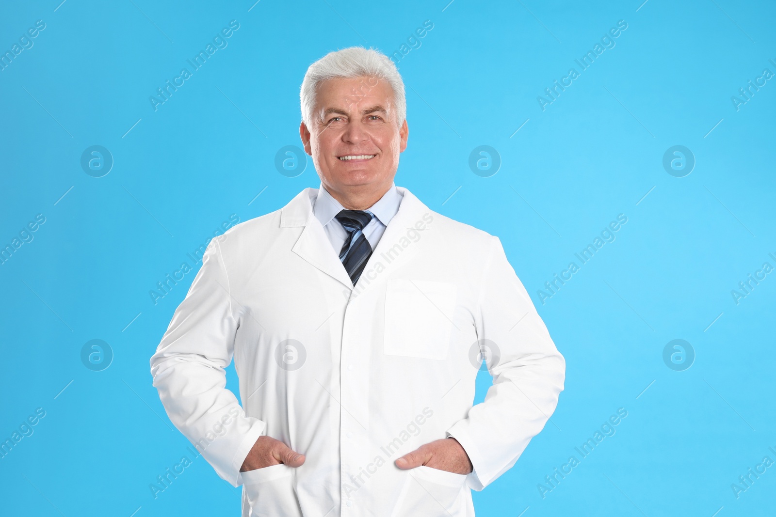 Photo of Happy senior man in lab coat on light blue background