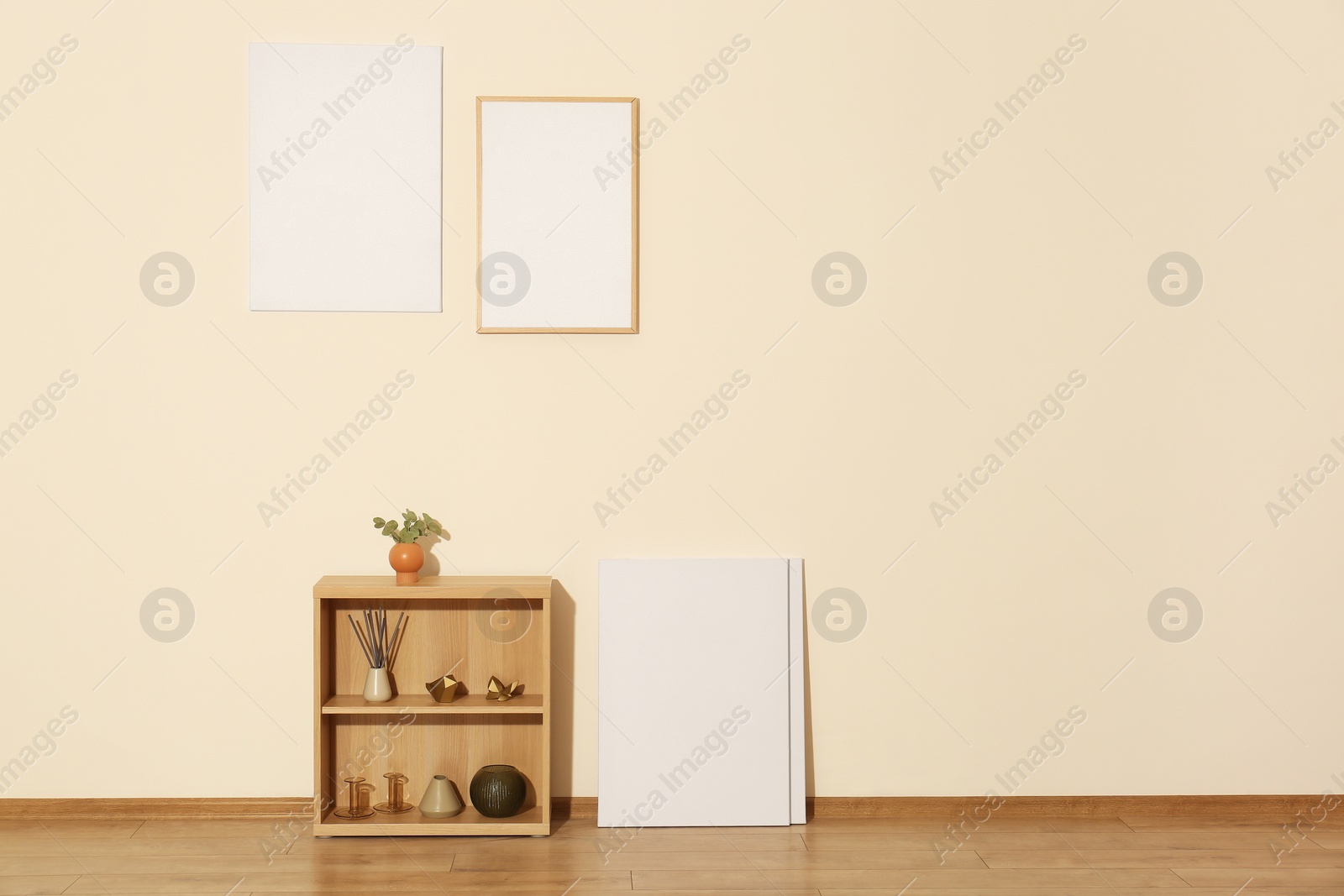 Photo of Wooden shelving unit and decor elements in room with beige wall, space for text. Interior design