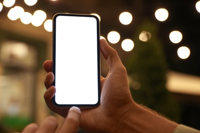 Photo of Man using modern mobile phone outdoors at night, closeup