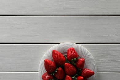 Food photography. Plate of delicious ripe strawberries on white wooden table, top view with space for text