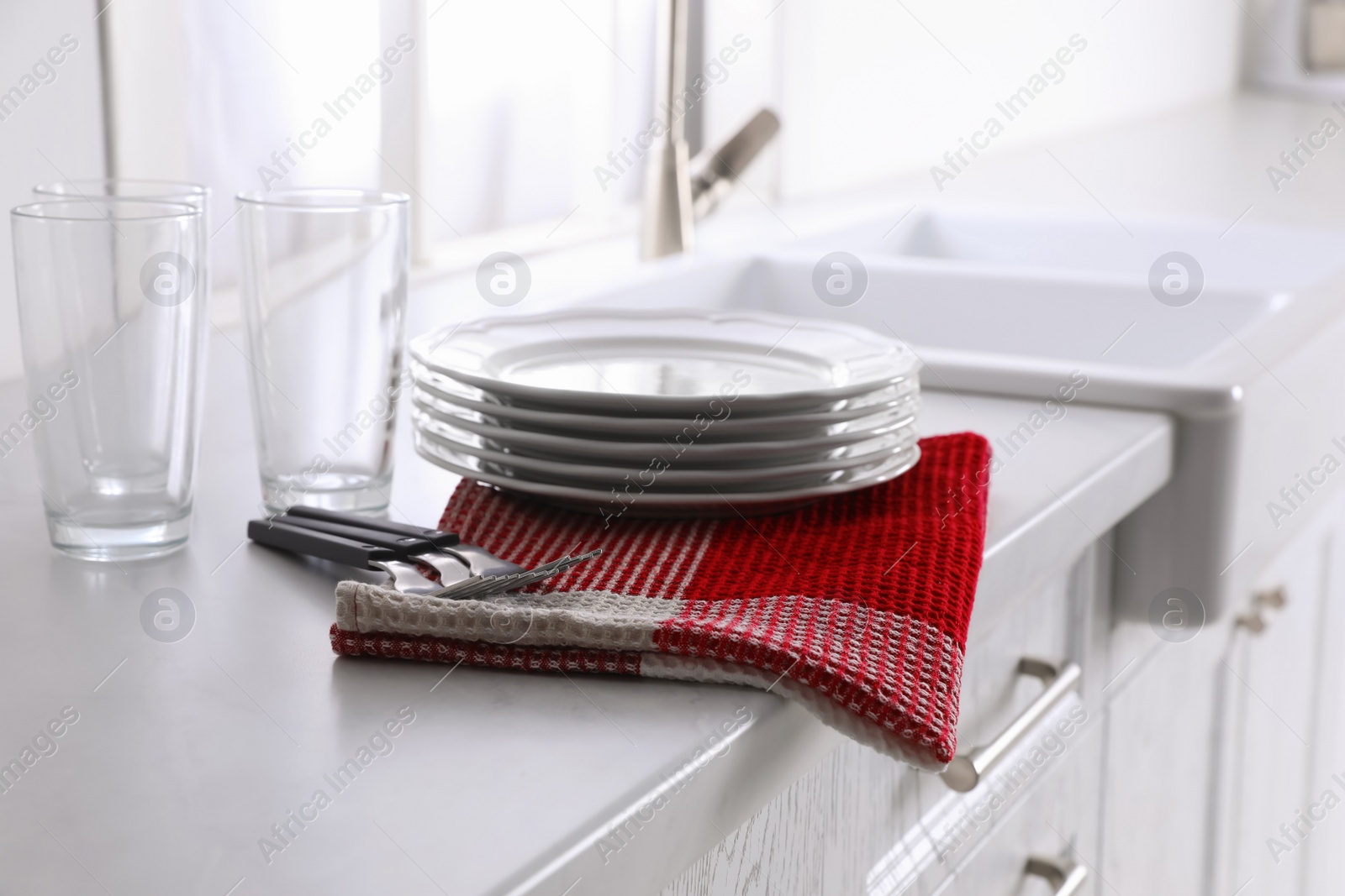 Photo of Dry towel and clean dishware on white countertop near sink in kitchen