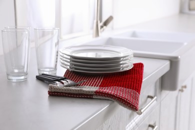 Dry towel and clean dishware on white countertop near sink in kitchen