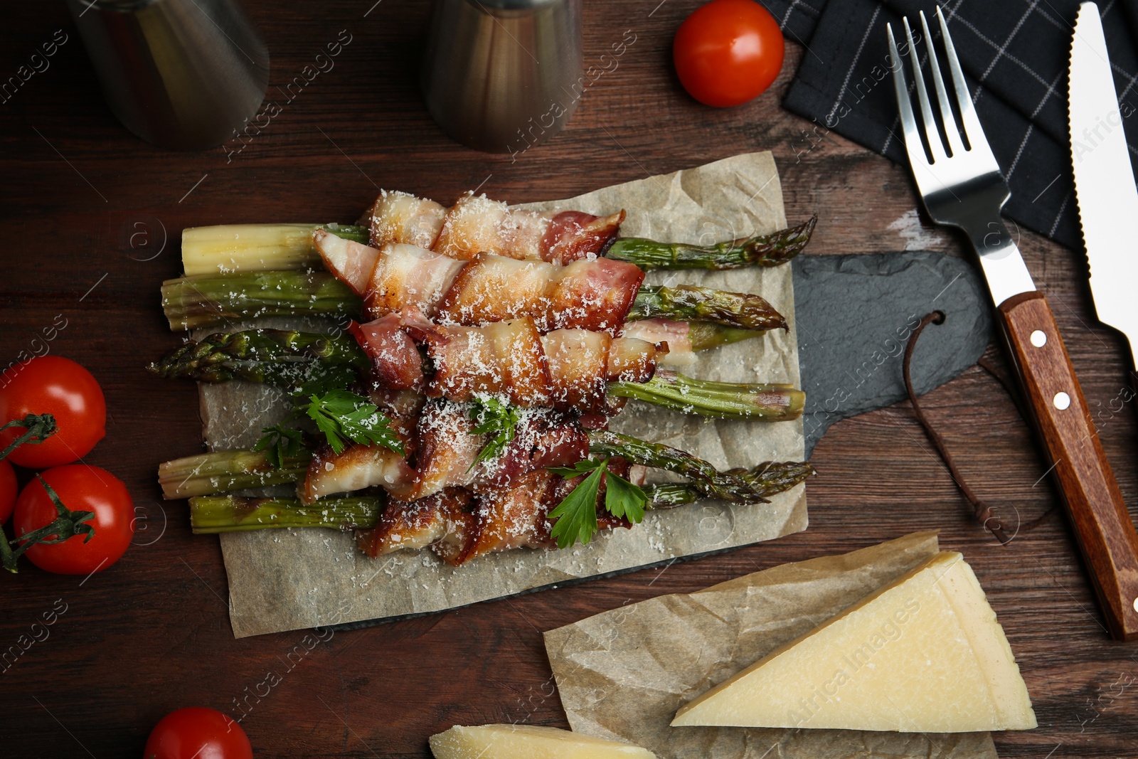 Photo of Oven baked asparagus wrapped with bacon on wooden table, flat lay