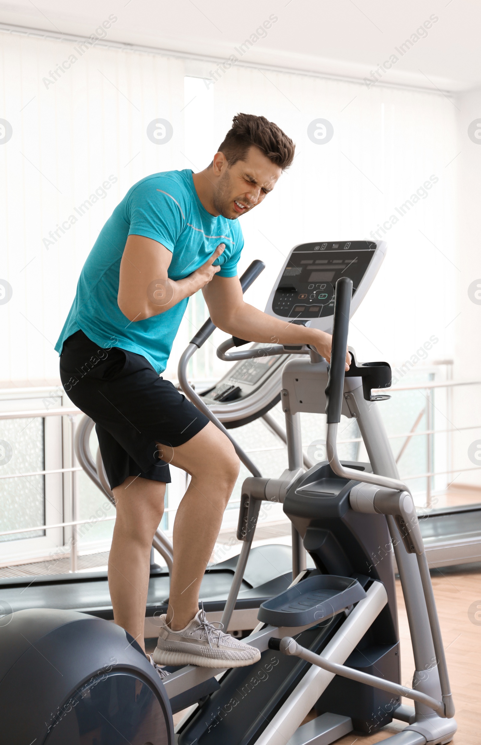 Photo of Young man having heart attack on treadmill in gym