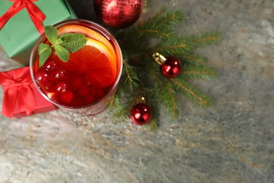 Photo of Aromatic Christmas Sangria in glass, gift boxes and festive decor on grey textured table, flat lay. Space for text