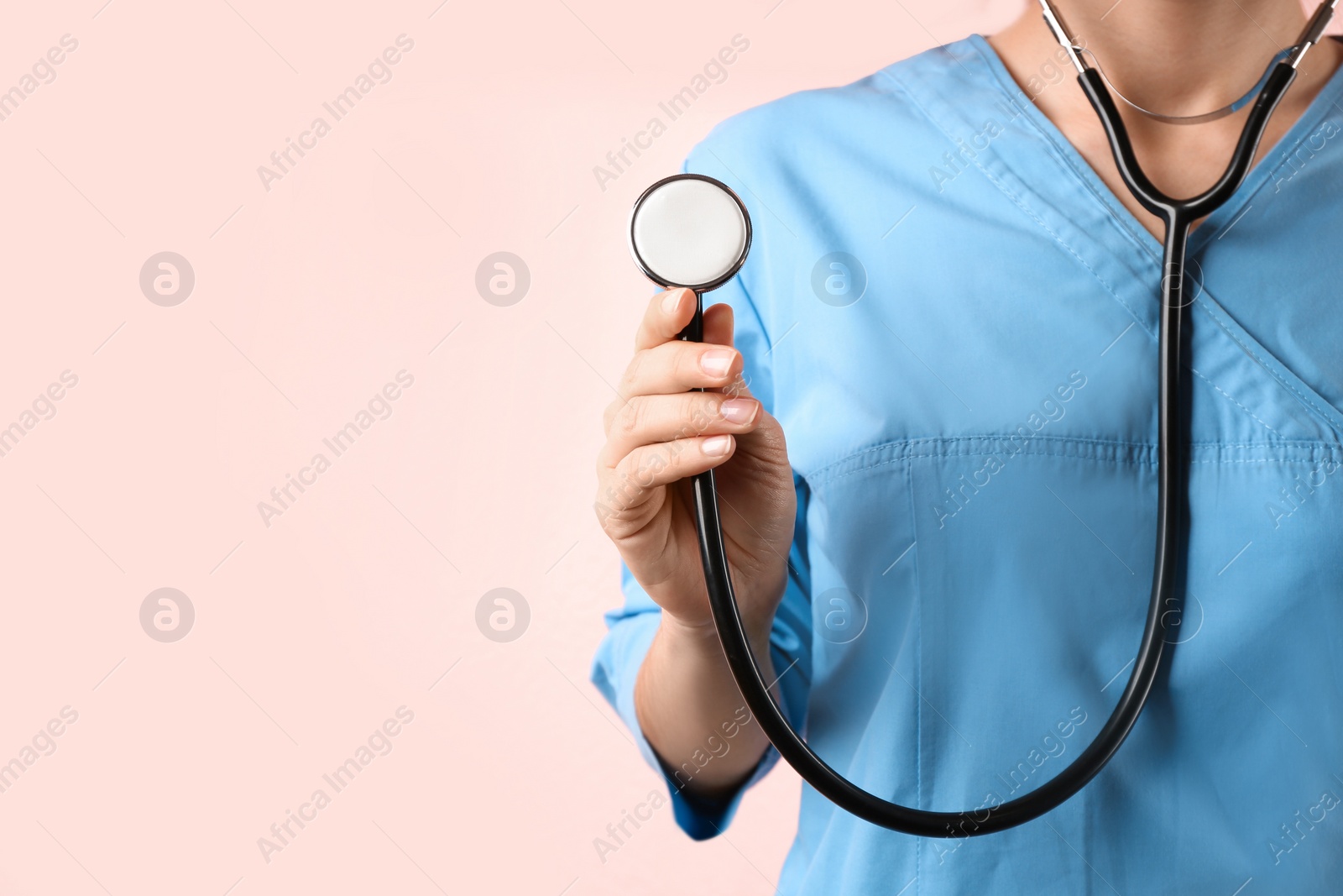 Photo of Doctor with stethoscope on pink background, closeup. Medical service