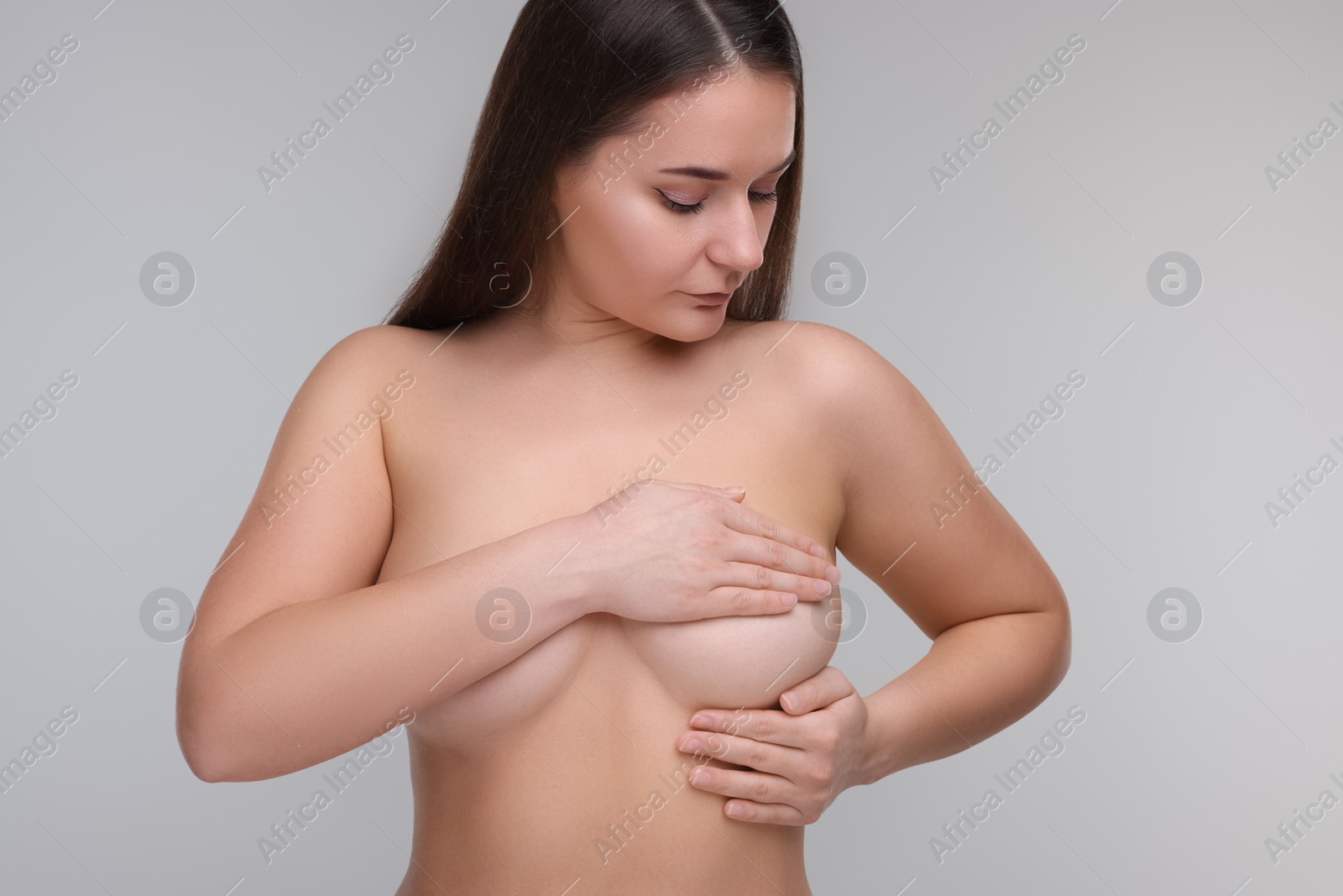 Photo of Mammology. Naked woman doing breast self-examination on light grey background