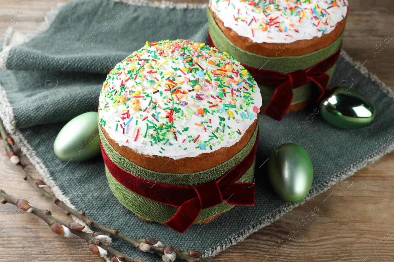 Photo of Traditional Easter cakes, painted eggs and willows on wooden table