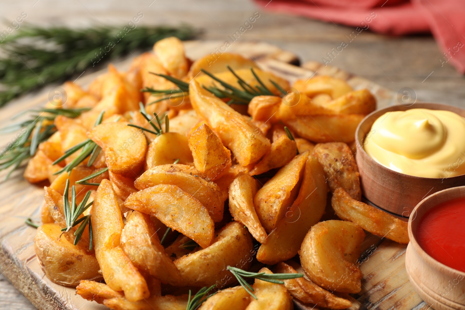 Photo of Baked potatoes served with rosemary, ketchup and mayonnaise on wooden board