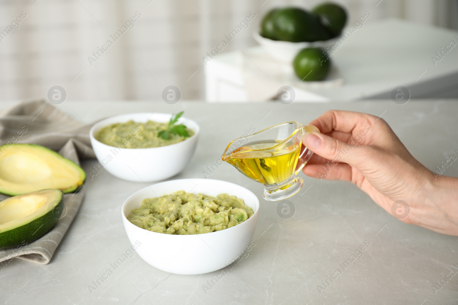 Photo of Woman preparing guacamole of ripe avocados at light table indoors, closeup. Space for text