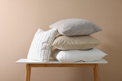 Photo of Soft pillows on table near beige wall