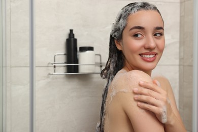 Photo of Happy woman washing hair in shower, space for text