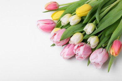 Photo of Beautiful colorful tulips on light background, closeup. Space for text