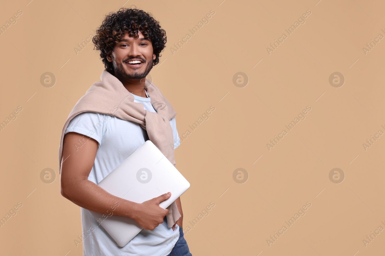 Photo of Smiling man with laptop on beige background, space for text