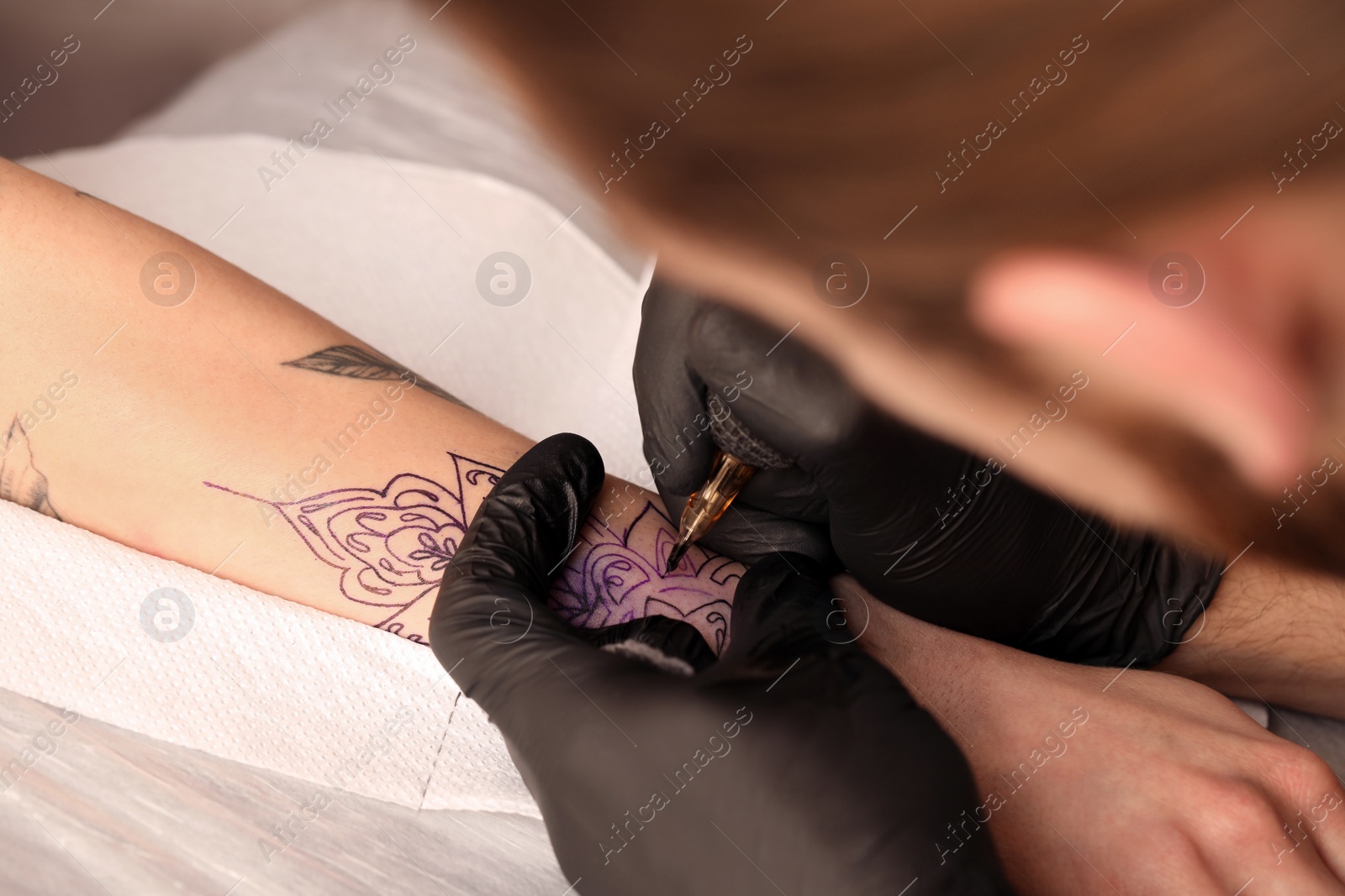 Photo of Professional artist making tattoo on hand at table, closeup