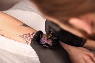 Professional artist making tattoo on hand at table, closeup