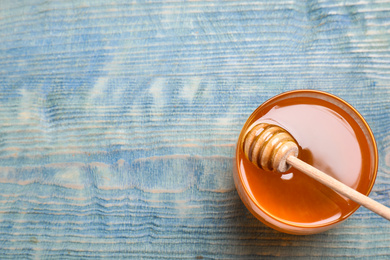 Photo of Tasty honey on light blue wooden table, top view. Space for text