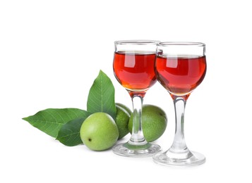 Photo of Delicious liqueur and green walnuts on white background