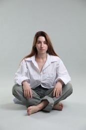 Photo of Beautiful young woman sitting on grey background