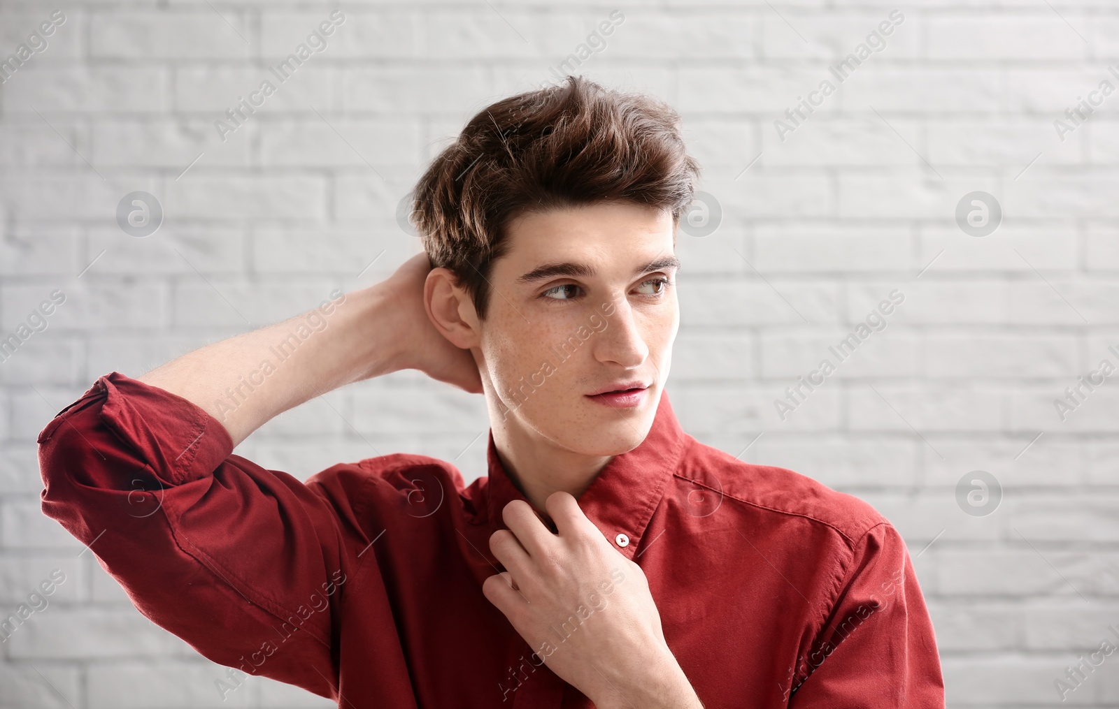 Photo of Portrait of young man with beautiful hair on brick wall background