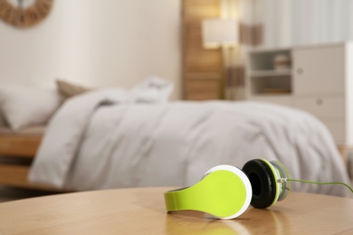 Photo of Stylish modern headphones with earmuffs on table against blurred background, space for text