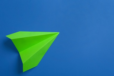 Photo of Green paper plane on blue background, top view. Space for text