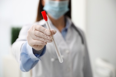 Photo of Doctor holding buccal cotton swab and tube for DNA test in clinic, closeup